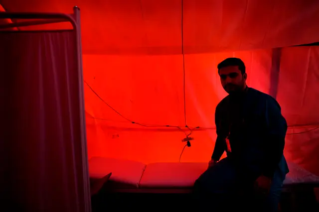 En syrisk læge sidder i den improviserede klinik i lejren. Før oprøret arbejdede han som plastik kirurg. For en uge siden fik han et opkald og blev spurgt om han ville lede klinikken her. Det tog ham fire dage at nå lejren, normalt ville køreturen tage under en dag, men på grund af de mange krigshandlinger er transporten dødsfarlig.